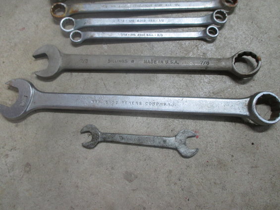 Several wrenches on a concrete surface, including a BILLINGS 7/8 wrench and a PENENS CORP wrench