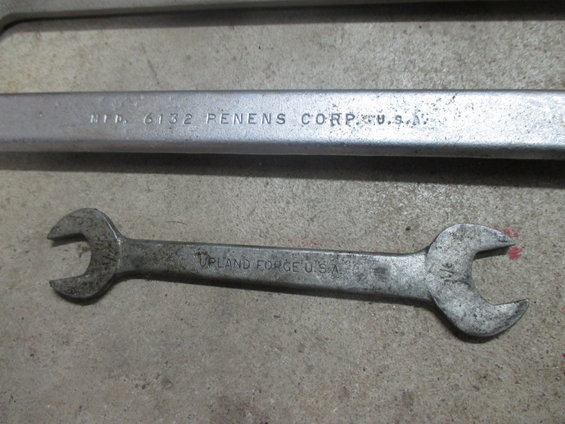 Two wrenches on a concrete surface. One is larger and has "MFD. 6132 RENENS CORP. U.S.A." stamped on it. The other is smaller and says "UPLAND FORGE U.S.A."