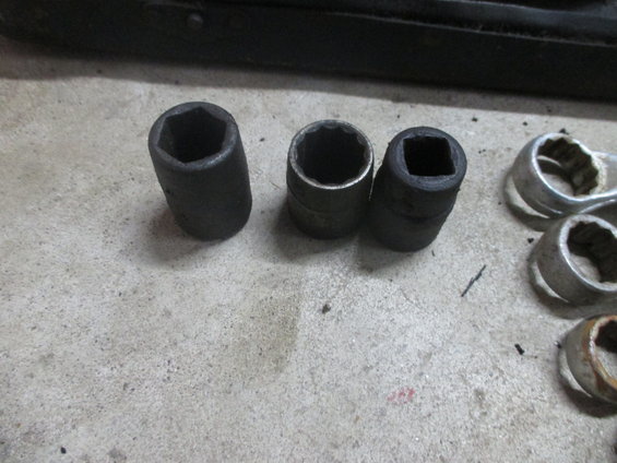 Three socket wrenches and other metal tools on a concrete surface