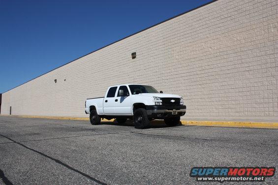 White 2006 Chevrolet Silverado 2500 parked in front of a beige brick wall