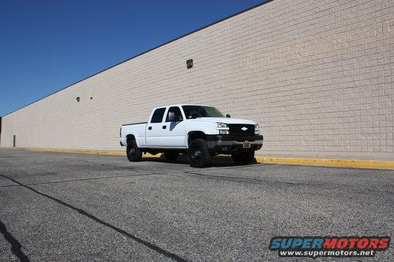 White 2006 Chevrolet Silverado 2500 parked in front of a beige brick wall