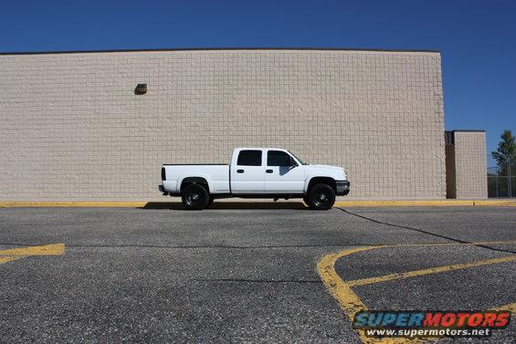 2006 Chevrolet Silverado 2500 pickup truck, side view, parked in front of a beige brick building