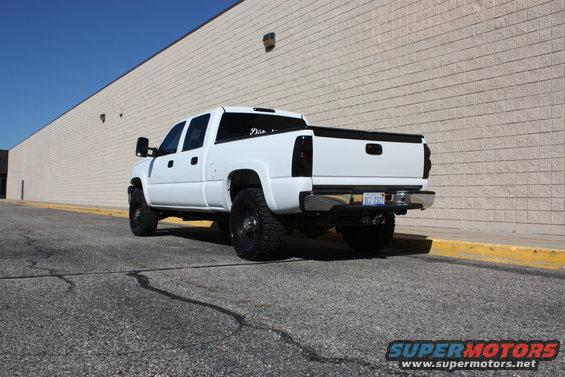 White pickup truck parked outside a building. It has tinted taillights and a license plate that reads BCT-2327