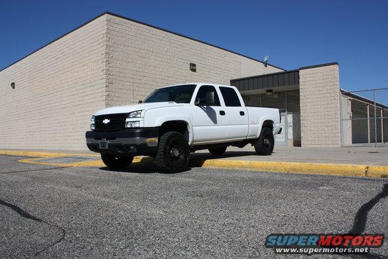 White 2006 Chevrolet Silverado 2500 pickup truck parked in front of a beige brick building