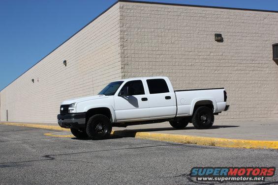 White 2006 Chevrolet Silverado 2500 pickup truck parked next to a brick building