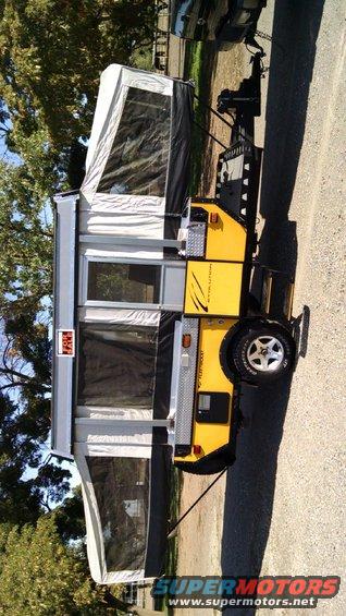 Yellow pop-up camper trailer with gray roof and white tent sections, parked outdoors. Text on side reads 'Fleetwood'