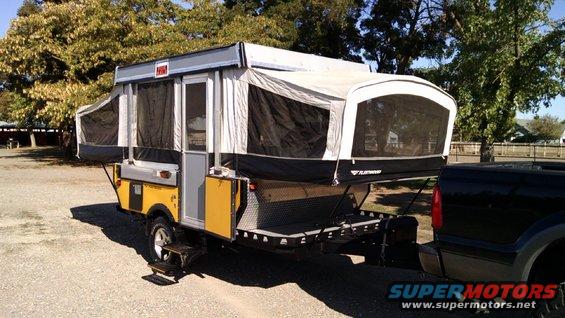 Yellow and gray pop-up camper trailer towed by black truck