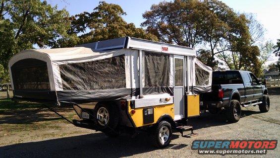 Black pickup truck towing a yellow and white pop-up camper trailer
