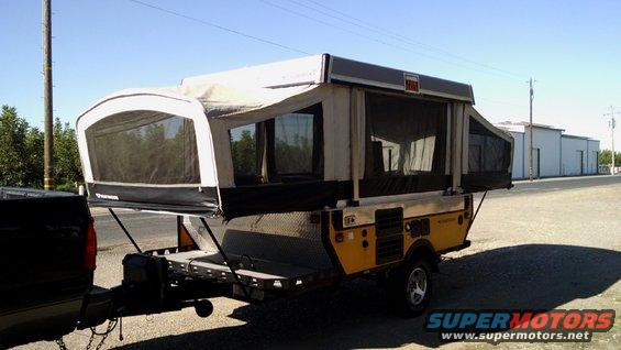 Pop-up camper trailer hitched to a dark-colored truck, parked outdoors