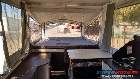 Interior view of pop-up camper with bed, table, and stove
