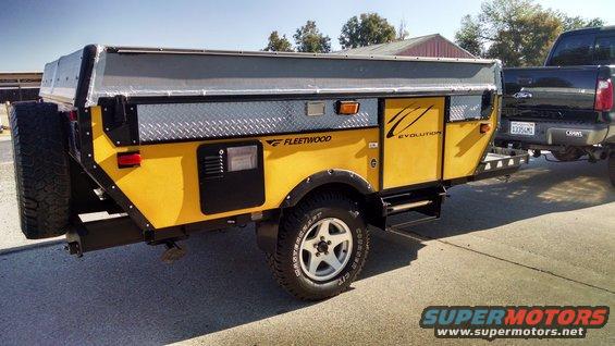 Yellow Fleetwood Evolution pop-up camper trailer towed by a black pickup truck