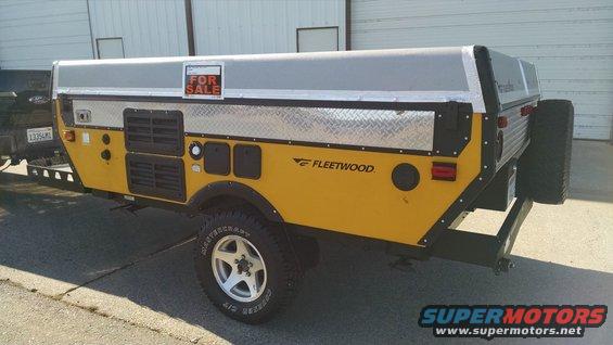 Yellow Fleetwood camper trailer with a 'For Sale' sign on top