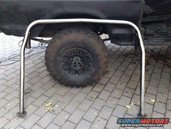 Black SUV rear fender and large off-road tire with a chrome roll cage in front