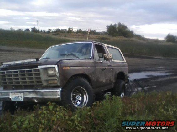 Brown Ford Bronco stuck in mud, front grille visible with license plate AJ86175