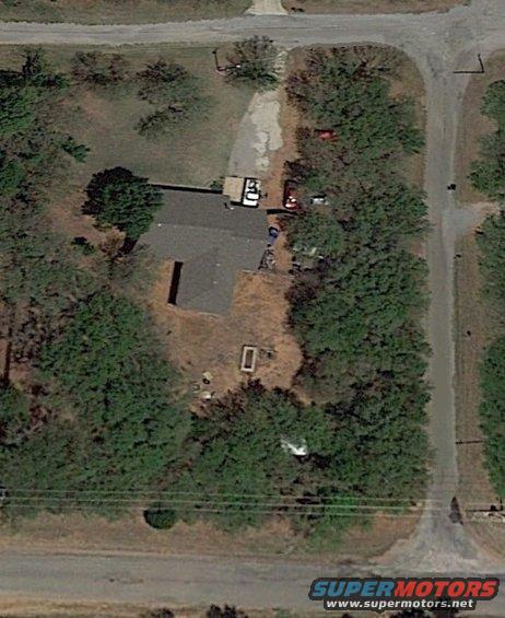 Aerial view of two red vehicles and a white vehicle parked near a house