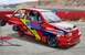 1991 Ford Festiva - A heavily modified red and yellow race car, possibly a Ford Festiva, is shown on jack stands with racing decals and sponsors visible.