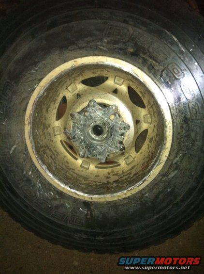 Wheel with a gold rim and a damaged silver hub, close-up