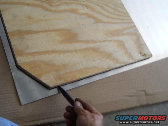 Plywood cut to shape over a metal sheet with a pencil marking the edge