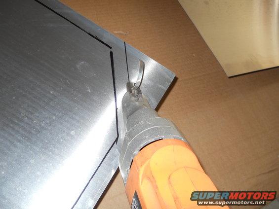 Electric shears cutting a line on a piece of sheet metal