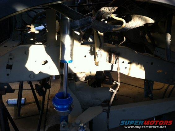 Close-up of a vehicle's suspension with a blue and silver shock absorber and tan frame
