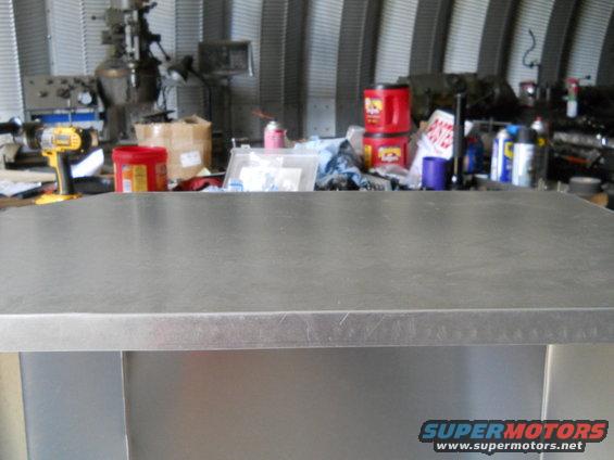 Metal workbench in a workshop with tools and supplies in the background