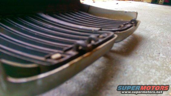 Car grille with horizontal black slats and a beige frame, showing rust spots and attachment clips