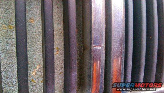 Close-up of a car grille with vertical bars, some textured and some shiny