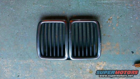 Pair of chrome-trimmed black BMW kidney grilles on a textured surface