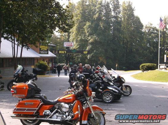 Several motorcycles are parked in front of a general store and archway at Deal's Gap
