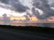 2011 Harley-Davidson Elec Gld Police - A dramatic sunset over the ocean, with dark clouds and power lines silhouetted against the colorful sky.