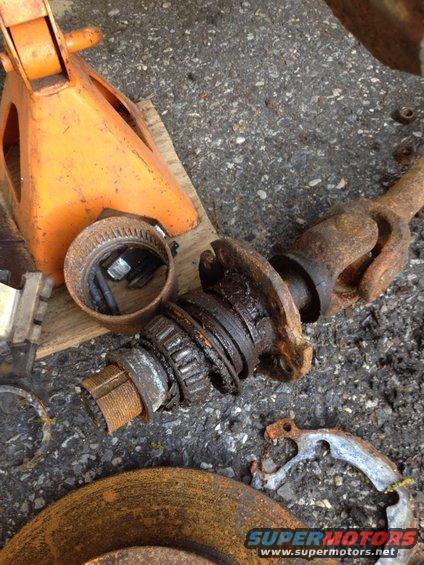 Disassembled wheel bearing and driveshaft parts on asphalt
