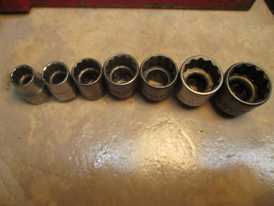 Socket set with seven metal sockets of varying sizes lined up on a textured surface