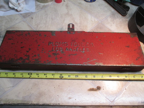 Red metal tool box with "PLOMB TOOL CO. LOS ANGELES." embossed on top