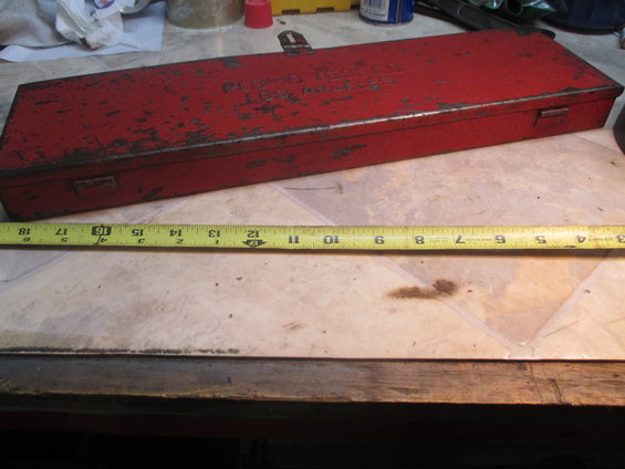 red metal toolbox with some text on top and a tape measure next to it
