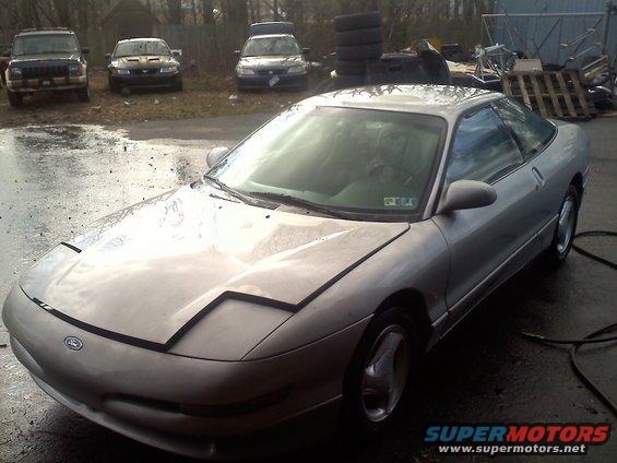 Silver 1993 Ford Probe GT parked outside with other cars and tires in the background