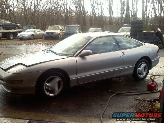 Silver 1993 Ford Probe coupe with pop-up headlights and alloy wheels, parked outdoors