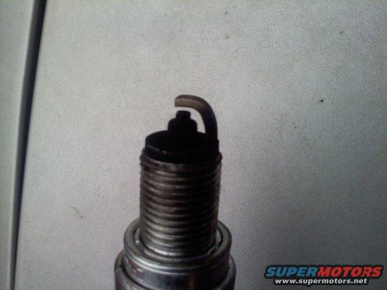 Close-up of a used spark plug with carbon buildup on the electrode