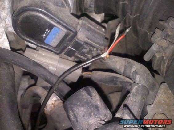 Engine wiring harness with frayed red and black wires connected to a black electrical component