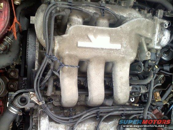 Close-up of a dirty engine intake manifold with multiple tubes and wires