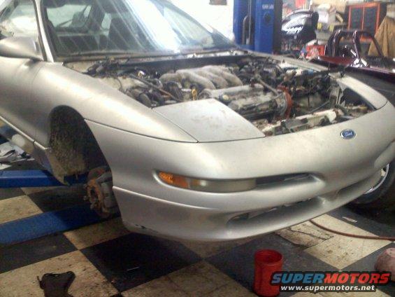 Silver 1993 Ford Probe GT coupe with hood open, engine exposed, on a lift in a garage