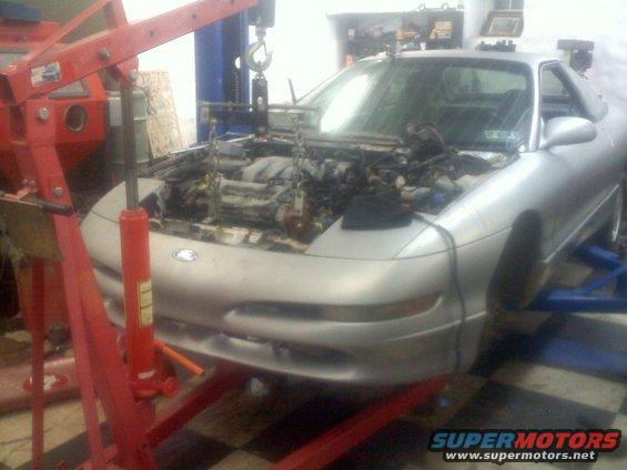 Silver 1993 Ford Probe coupe on a lift with engine removed, front view