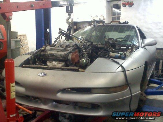 1993 Ford Probe GT with engine being lifted out by a red engine hoist. The car is silver and in a workshop