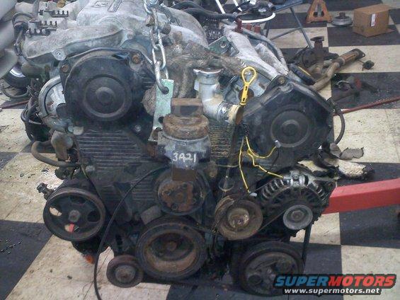 Engine block with timing covers, pulleys, alternator, and yellow dipstick. Part number 3421 visible