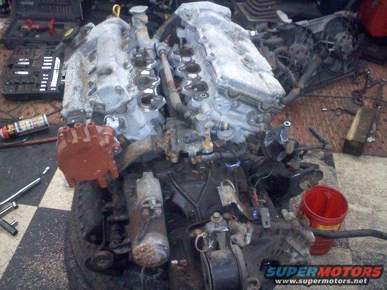 V6 engine with distributor cap removed, tools and parts scattered around