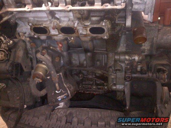 Close-up of a dirty engine block with intake manifold and hoses attached