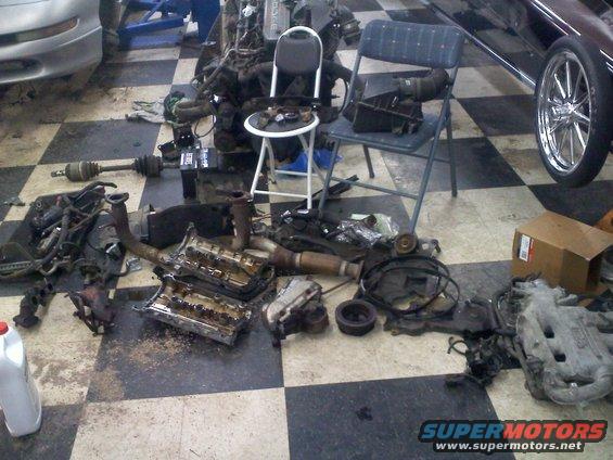Disassembled engine parts on a checkered garage floor