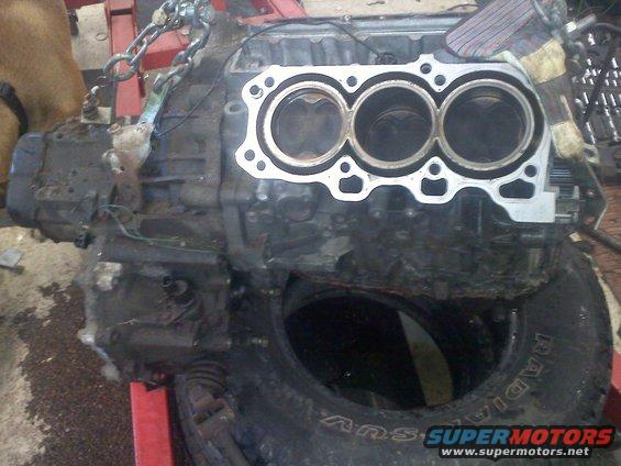 Engine block with three pistons visible, on a stand