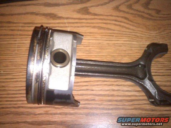 Piston with rings and connecting rod assembly on a wooden surface