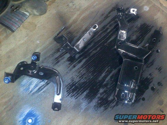 Three black painted metal brackets on a wooden surface
