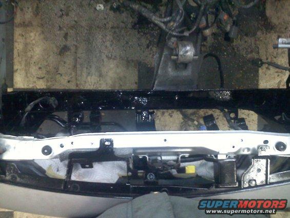 car's front end with engine components visible above a black crossmember